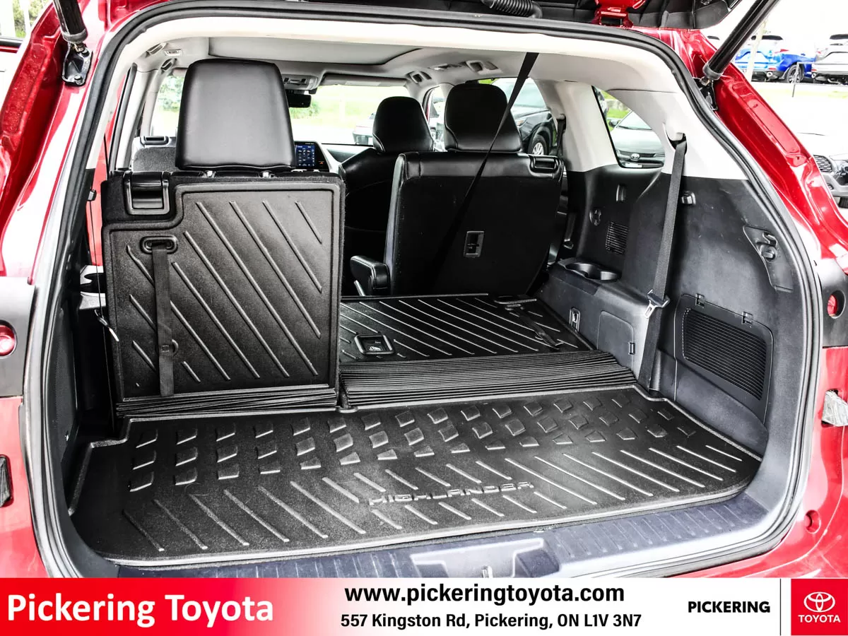 Rear view of a trunk open, showcasing the spacious cargo area and folded-down rear seats of a red 2022 Toyota Highlander Hybrid Limited AWD SUV taken