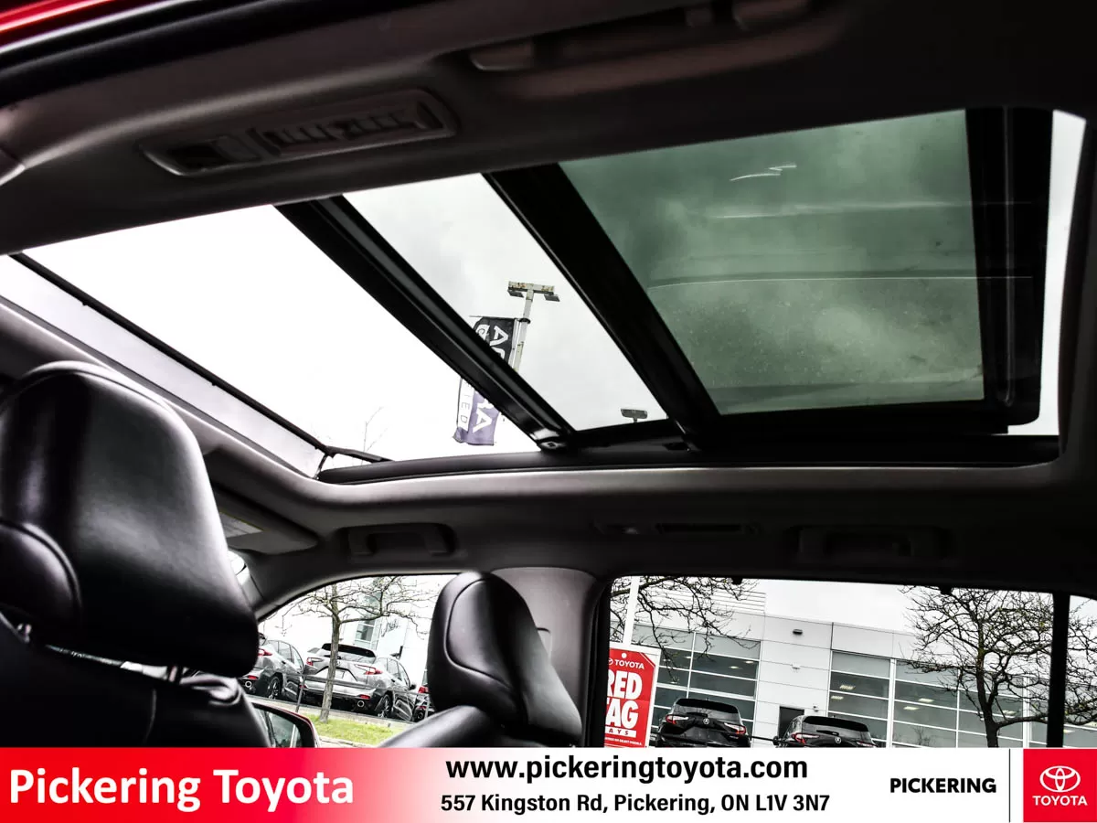 Interior view of a Toyota vehicle showing the open panoramic sunroof and black leather seats of a red 2022 Toyota Highlander Hybrid Limited AWD SUV ta