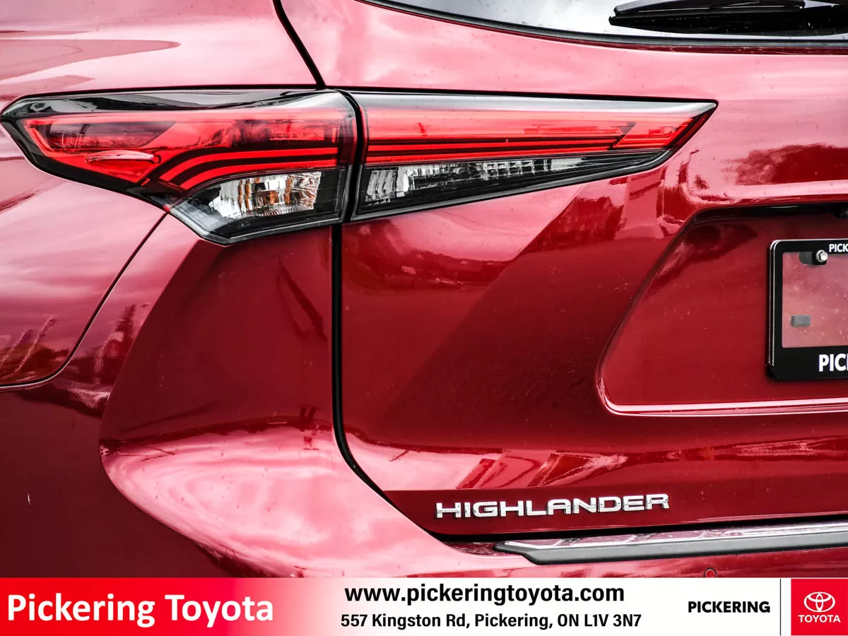 Close-up view of the rear of a red 2022 Toyota Highlander Hybrid Limited AWD SUV parked in front of the Pickering Toyota dealership