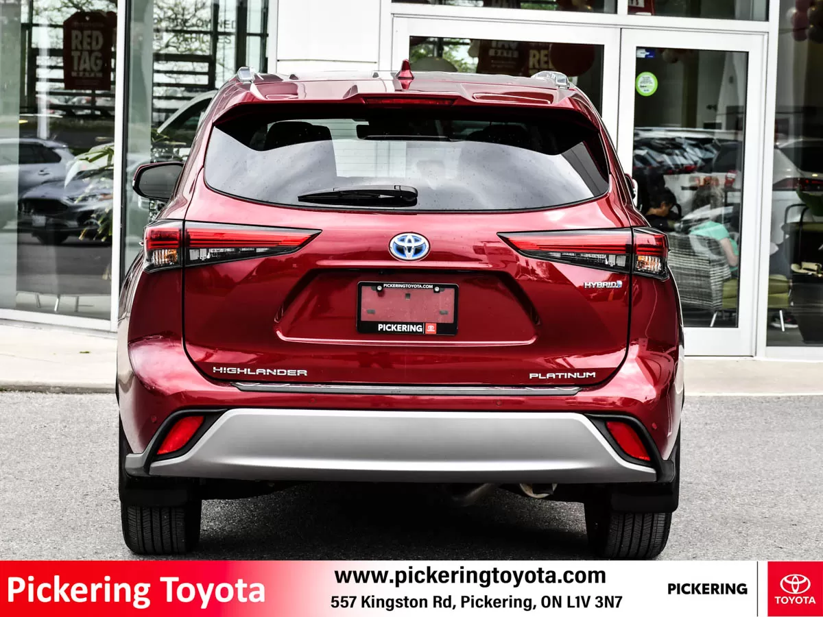 Rear view of a red 2022 Toyota Highlander Hybrid Limited AWD SUV Platinum package parked in front of Pickering Toyota dealership