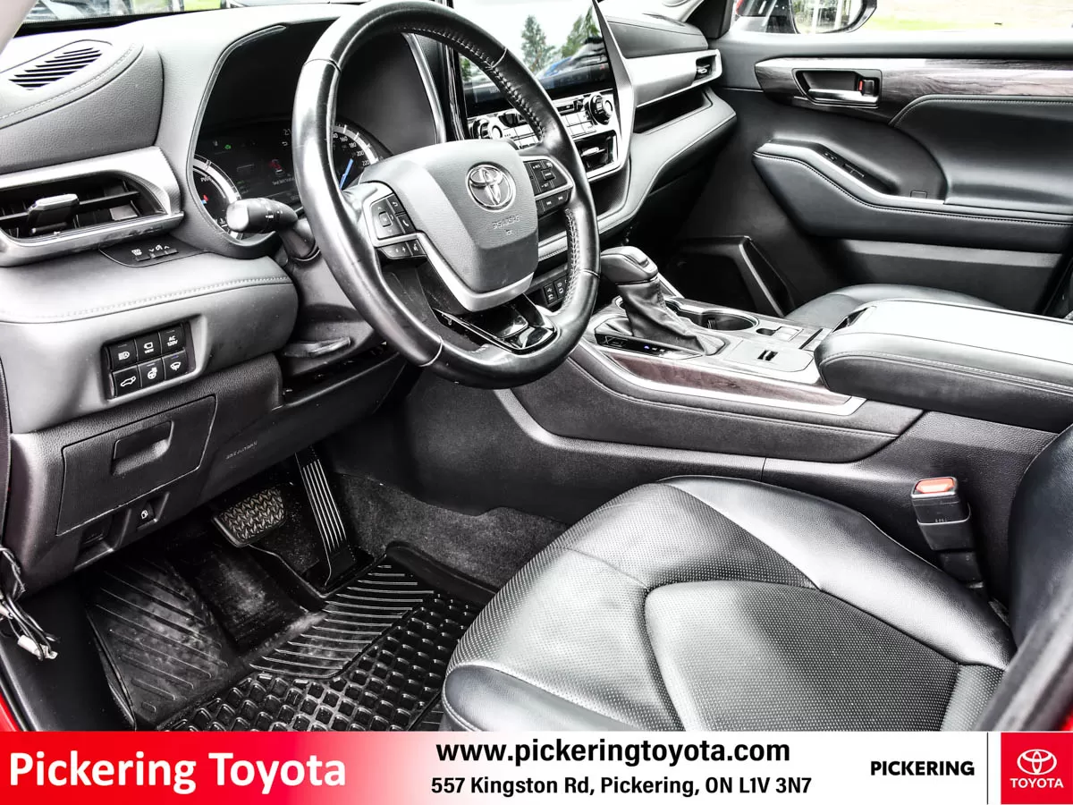 Interior view showcasing the steering wheel, dashboard, and front seats of a 2022 Toyota Highlander Hybrid Limited AWD SUV at Pickering Toyota dealers